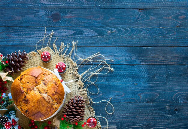 Gâteau de Noël panettone au chocolat italien avec des cônes en épingle à cônes de décorations babiole sur un fond en bois.