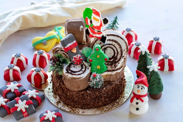 Gâteau de Noël préparé avec de la pâte à sucre Avec le sapin de Noël du père noël et des figurines cadeaux dessus