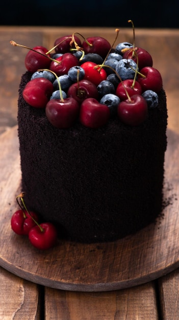 Gâteau noir avec des baies sur le dessus Un gâteau décoré de myrtilles et de cerises