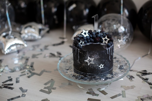 Gâteau noir avec des étoiles et des baies sur une plaque de verre