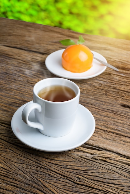 Gâteau orange à la forme orange sur la table en bois de grunge et tasse de thé