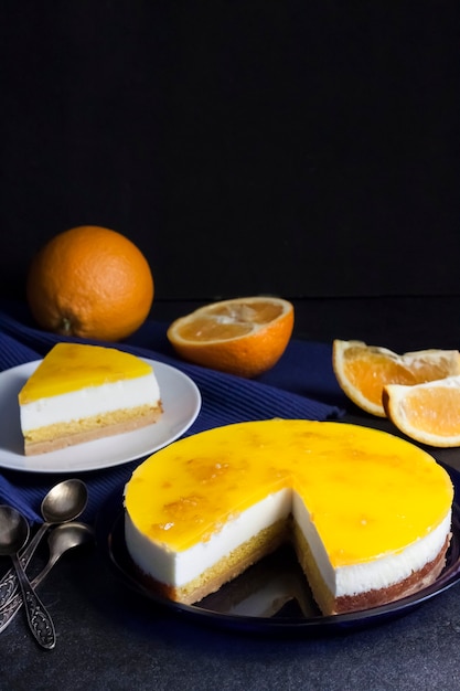 Gâteau à l'orange avec mousse à la crème et gelée d'orange sur fond sombre