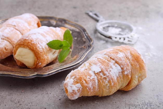 Gâteau "paille" fourré à la crème, décoré de sucre en poudre et de feuilles de menthe