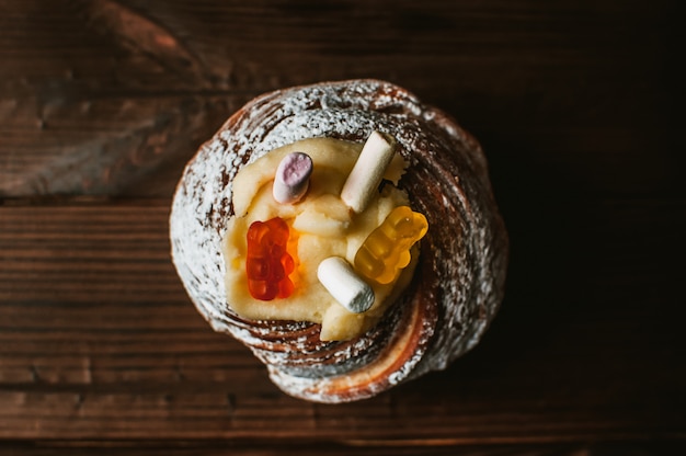 Gâteau de Pâques élégant avec des guimauves et de la gelée porte sur un fond en bois rustique foncé.