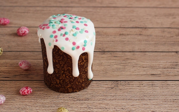 Gâteau de Pâques en forme brune en glaçure blanche saupoudré sur un fond en bois