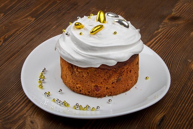 Gâteau de Pâques kulich Pain traditionnel de Pâques décoré de meringue et d'oeufs en forme de canne en bonbon sur une assiette sur fond de table en bois