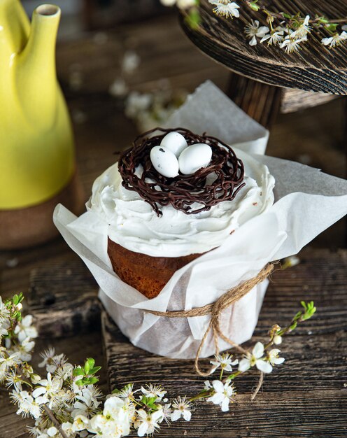 Gâteau de Pâques avec des œufs blancs dans un nid de chocolat sur la table en bois