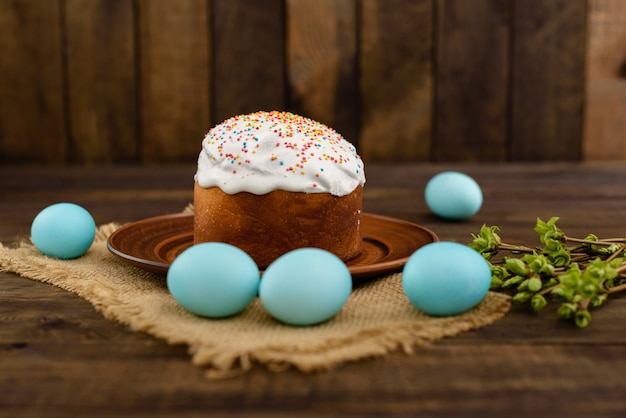 Gâteau de Pâques et oeufs colorés sur une table en bois.