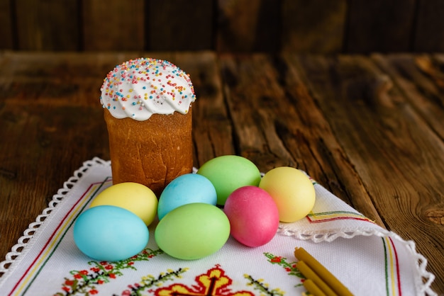 Gâteau de Pâques et oeufs colorés sur une table en bois.