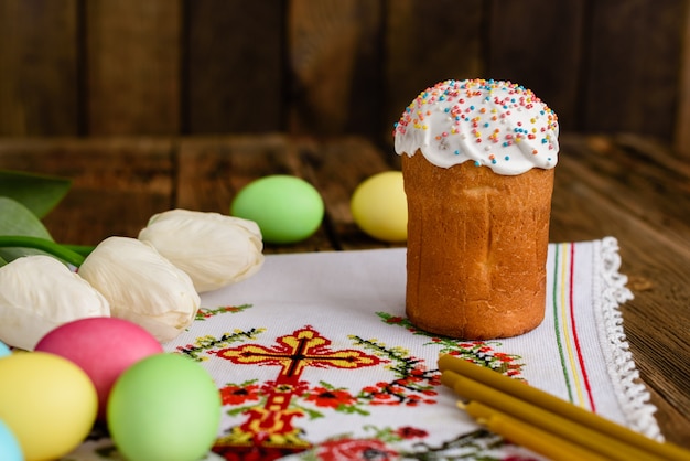 Gâteau de Pâques et oeufs colorés sur une table en bois.