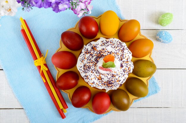 Gâteau de Pâques et oeufs peints sur une assiette sur un fond en bois. Thème de Pâques. Vue de dessus.