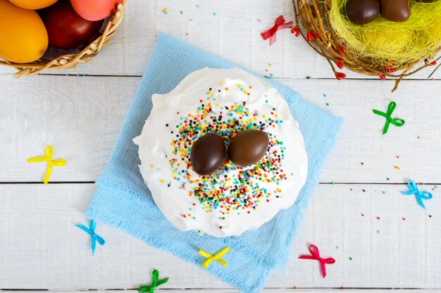 Gâteau de Pâques traditionnel - kulich et oeufs en chocolat dans un nid sur un fond blanc en bois. Pain sucré décoré de meringue. Vue de dessus. Thème de Pâques.