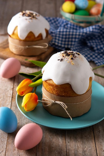 Photo gâteau de pâques traditionnel, oeufs colorés et tulipes sur table en bois.