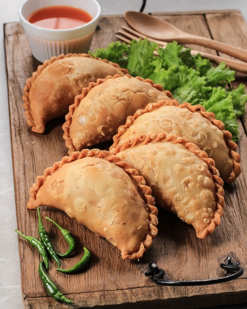 Gâteau Pastel indonésien servi sur une assiette blanche accompagné de thé. Populaire comme Curry Puff (Karipap) ou Jalangkote Makasar.