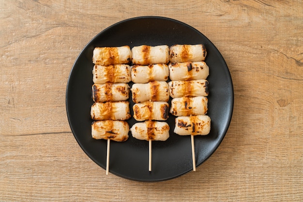 Photo gâteau de pâte de poisson grillé en forme de tube ou brochette de calmar en tube sur assiette