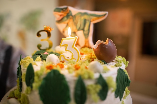 Gâteau avec une photo d'un œuf de dinosaure et d'un tyrannosaurus rex en arrière-plan bougie numéro 3