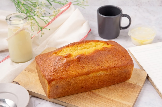 Gâteau quatre-quarts avec glaçage au citron sur une planche à découper, lait dans une bouteille en verre.