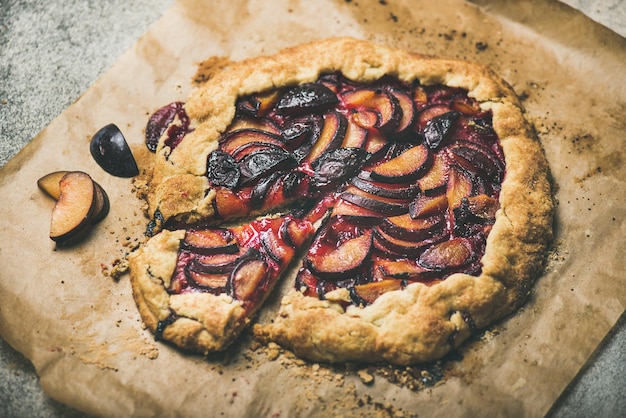 Gâteau rond de galetta aux prunes sur papier sulfurisé sur fond de béton