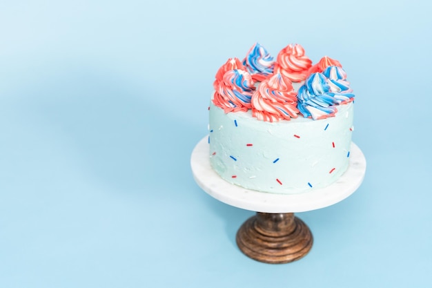 Gâteau rond rouge, blanc et bleu givré avec un glaçage à la crème au beurre.