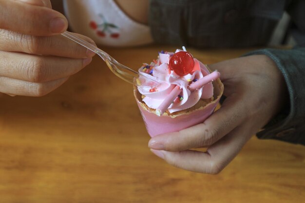 Un gâteau rose et une main féminine dans le café.