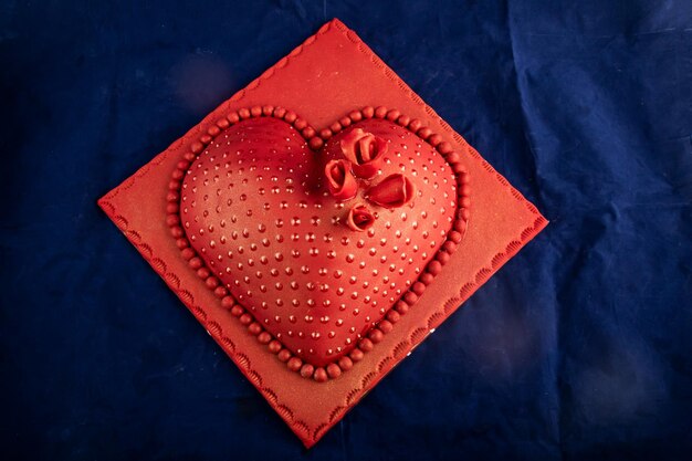 Gâteau rouge en forme de coeur avec couteau et fourchette à fleurs roses servi à bord isolé sur une serviette vue de dessus des aliments cuits au café