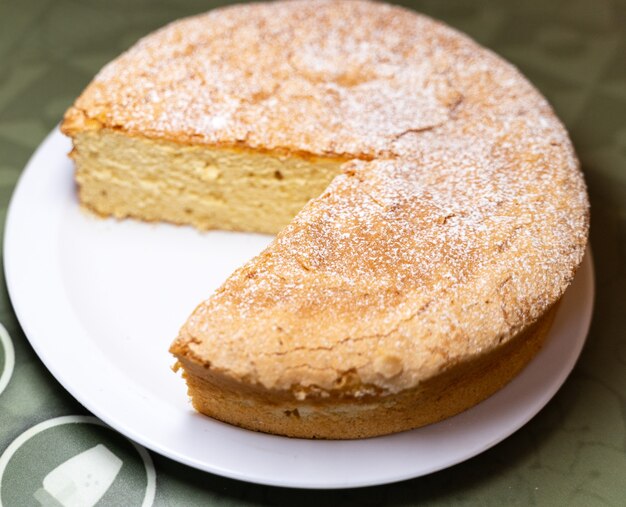 Gâteau santiago incomplet avec une tranche manquante sur une plaque blanche dans un restaurant