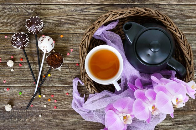 Le gâteau saute. Bonbons ronds sur un bâton dans un glaçage au chocolat. Une tasse de thé.