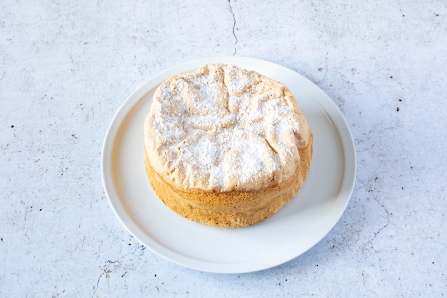 Gâteau de Savoie fait maison sur un joli plat en porcelaine blanche