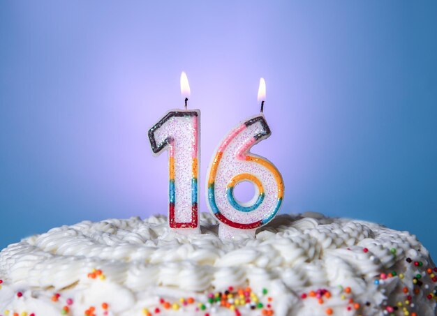 Gâteau savoureux avec des bougies pour le seizième anniversaire sur fond bleu