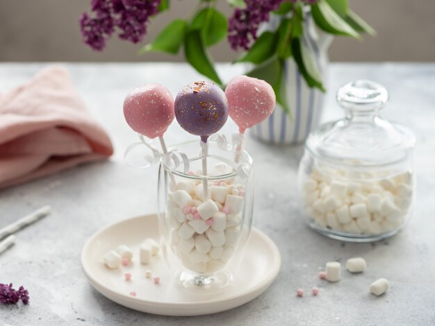 Gâteau sucré coloré apparaît dans un verre plein de guimauves sur une table grise. concept de vacances