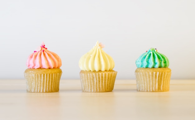 Gâteau de tasse de couleur de trois pastels s&#39;alignant sur la table blanche.