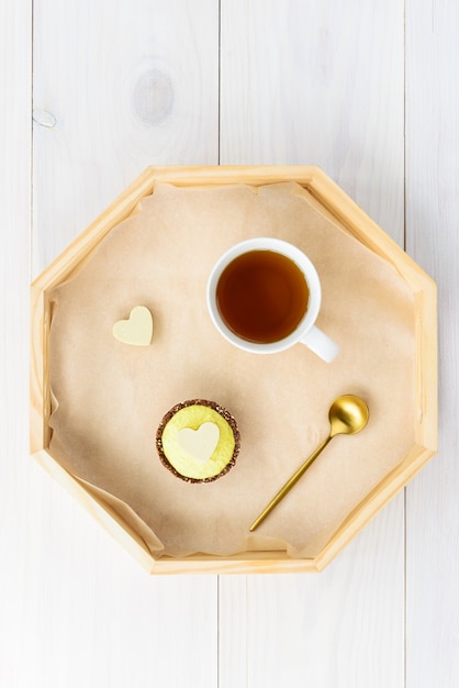 Gâteau avec une tasse de thé sur un plateau sur une table en bois