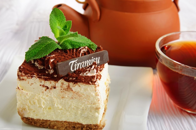 Gâteau tiramisu au chocolat avec une tasse de thé sur blanc