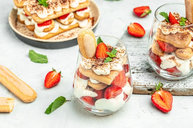 Gâteau tiramisu au dessert italien avec biscuit fraise fraîche et crème fouettée et menthe sur fond clair Dessert végétalien sans lactose