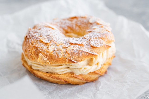 Gâteau traditionnel français Paris Brest avec crème pralinée sucre en poudre et pétales d'amandes