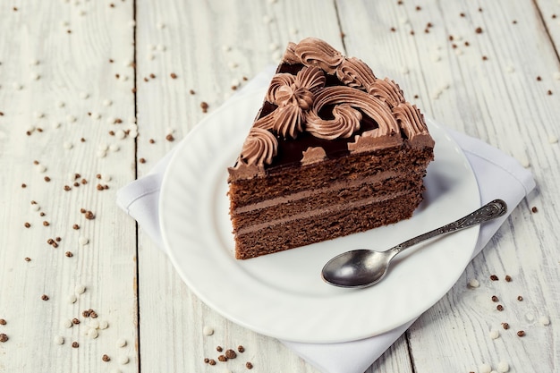 Gâteau végétalien au chocolat noir avec des bonbons et de la crème sur fond de bois