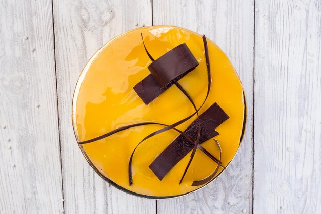 Gâteau végétalien au chocolat noir avec crème soufflée et glaçage miroir aux fruits sur fond de bois