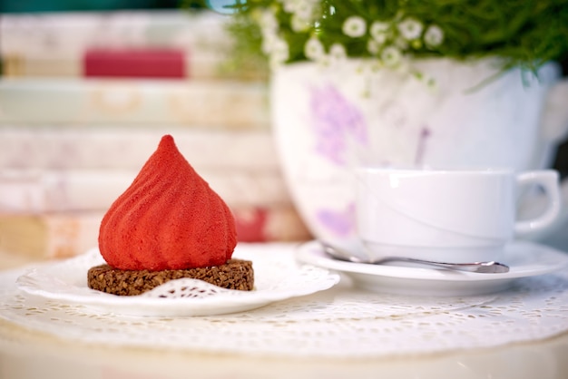 Gâteau de velours avec du thé sur la table avec des fleurs et des livres.