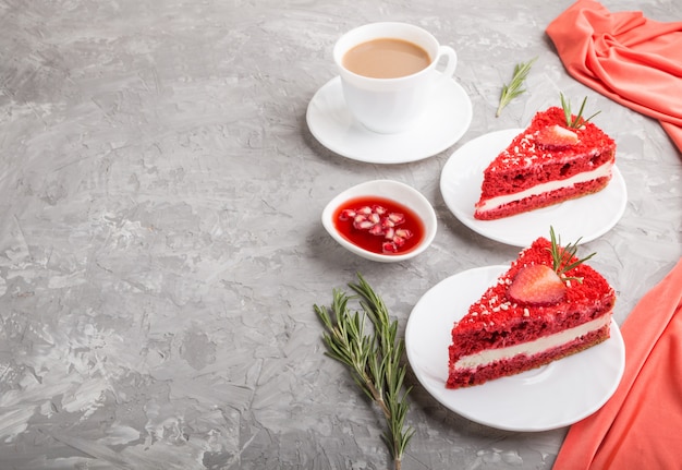 Gâteau de velours rouge fait maison avec de la crème de lait et des fraises avec une tasse de café sur une surface en béton gris. vue latérale, espace copie.