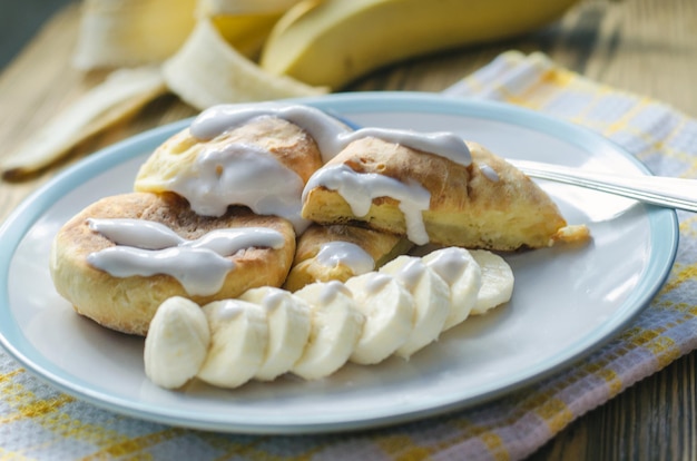 Gâteaux au fromage avec banane et crème sure sur un gros plan de plaque