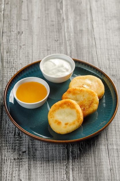 Gâteaux au fromage cottage servis avec du miel et de la crème sure