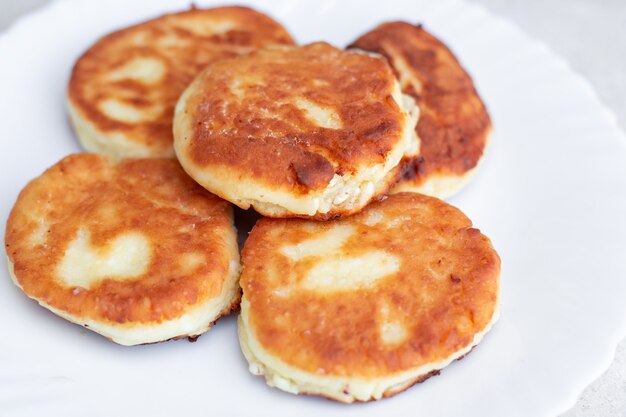 Gâteaux au fromage frits frais sur une plaque blanche en gros plan un délicieux petit-déjeuner sain