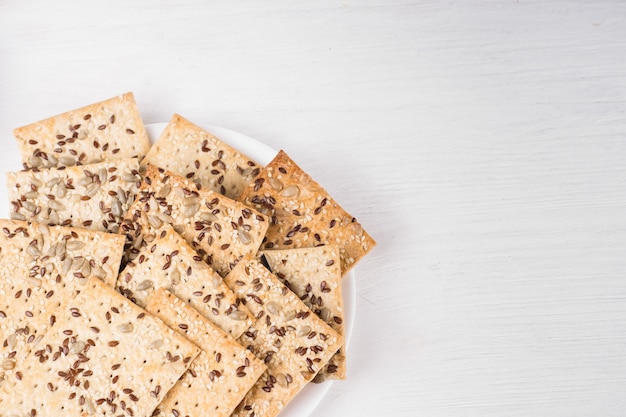 Gâteaux de blé croustillants avec graines de sésame, de lin et de tournesol sur plaque sur fond en bois blanc. nourriture végétarienne, concepts alimentaires écologiques