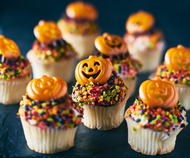 Photo des gâteaux de citrouille festifs d'halloween avec du glaçage au chocolat et des saupoudres colorées