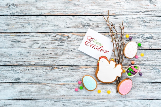 Gâteaux colorés de Pâques oeufs décoratifs et bonbons Carte de voeux Sur un fond en bois blanc Vue de dessus espace de copie gratuit