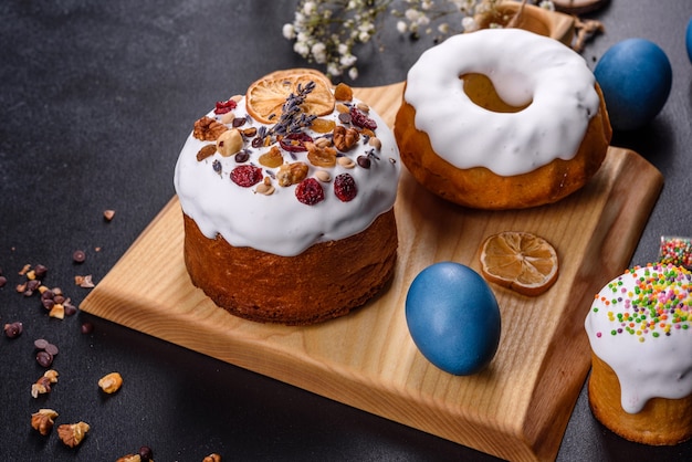 Gâteaux de fête avec glaçage blanc, noix et raisins secs avec des œufs de Pâques sur la table de fête. Préparatifs de Pâques