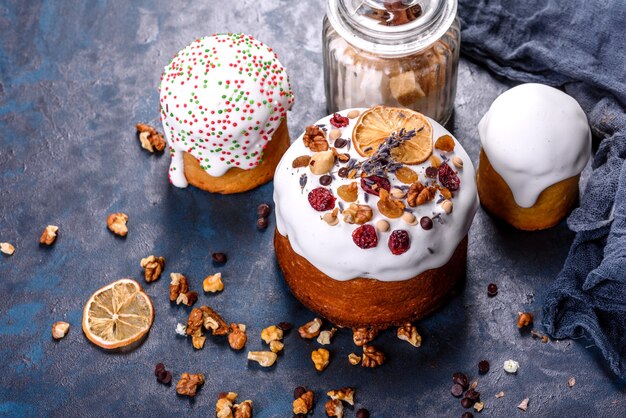 Gâteaux de fête avec glaçage blanc, noix et raisins secs avec des œufs de Pâques sur la table de fête. Préparatifs de Pâques