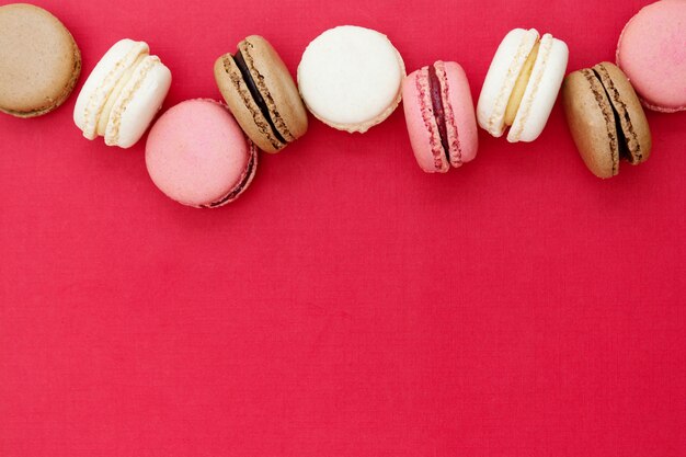 Gâteaux de macarons ou biscuits sur fond rouge. Mise à plat. Copiez l'espace.