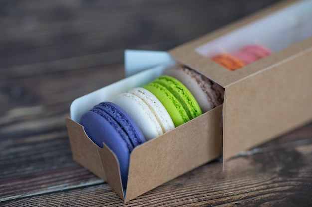 Gâteaux de macarons colorés dans une boîte en papier sur une table en bois