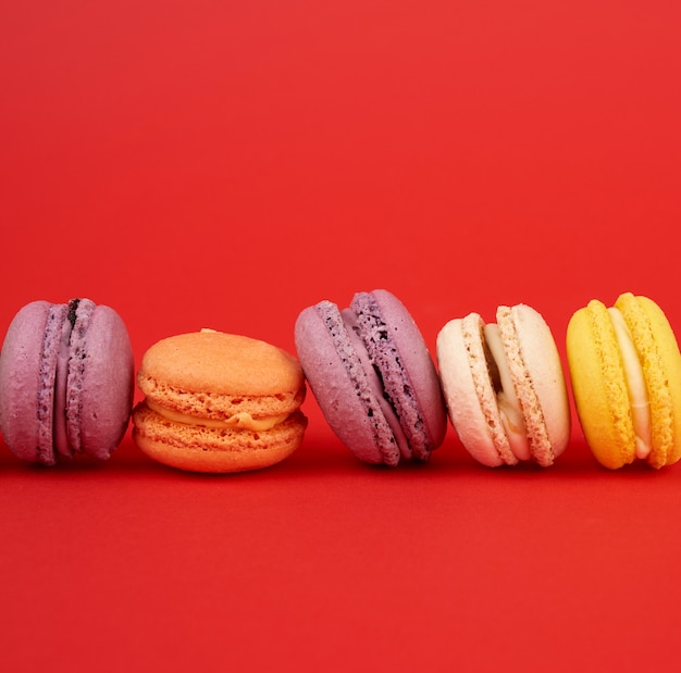 Gâteaux macarons cuits au four jaune, violet, vert sur fond rouge